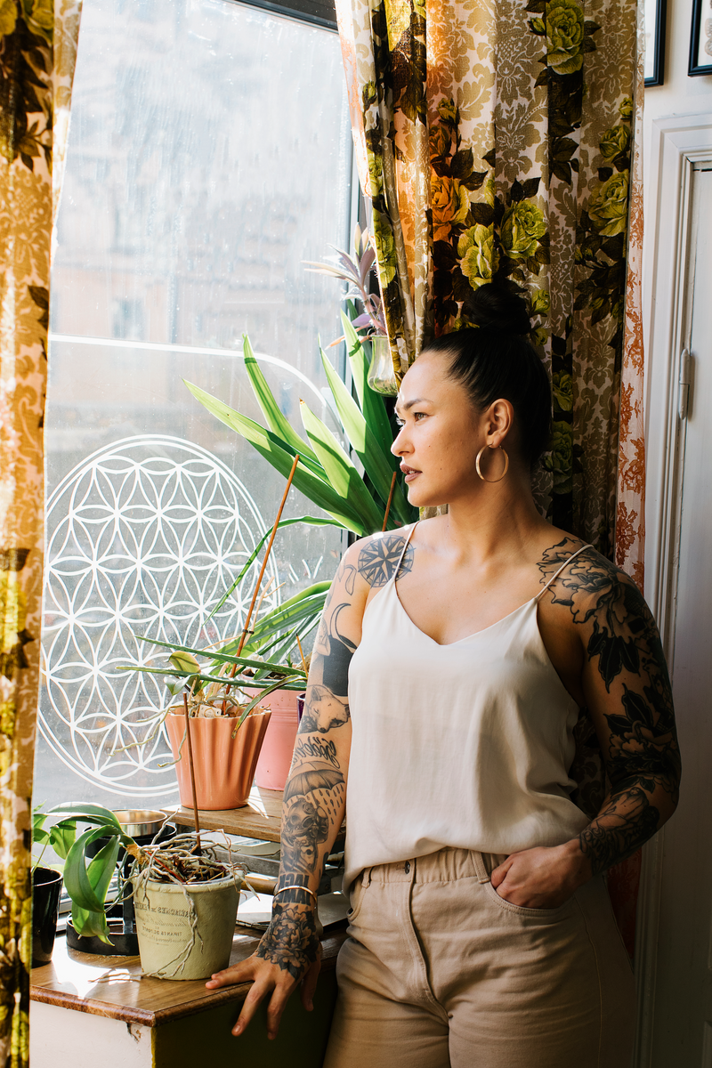 kvinna som tittar ut från fönstret från en tatueringsstudio
